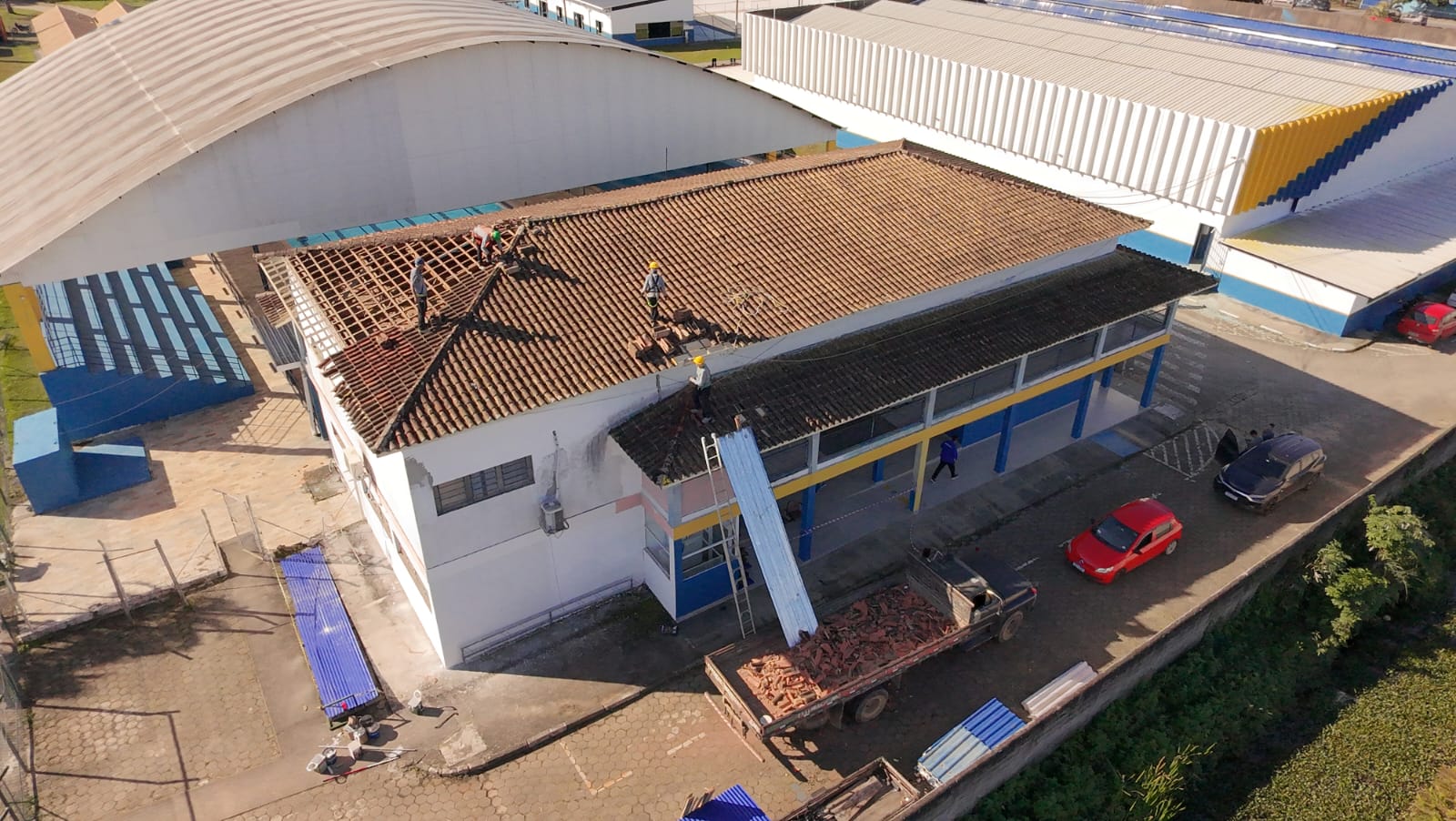 Equipe executando reforma de cobertura em edifício industrial